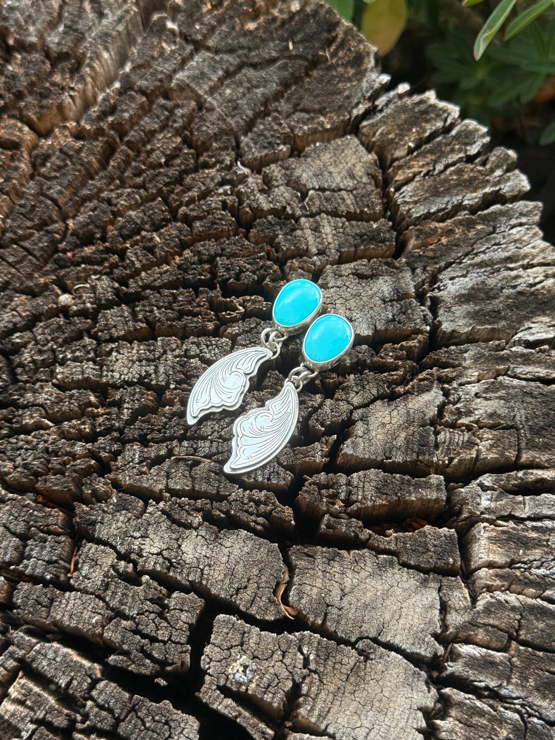 Silver earrings with blue stones on a textured wooden surface