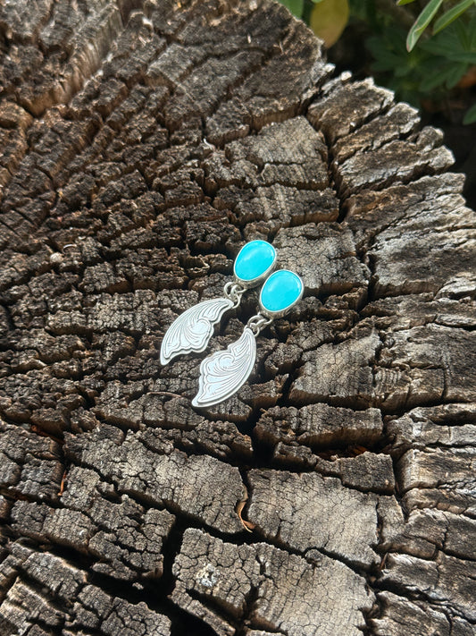 Silver earrings with blue stones on a textured wooden surface
