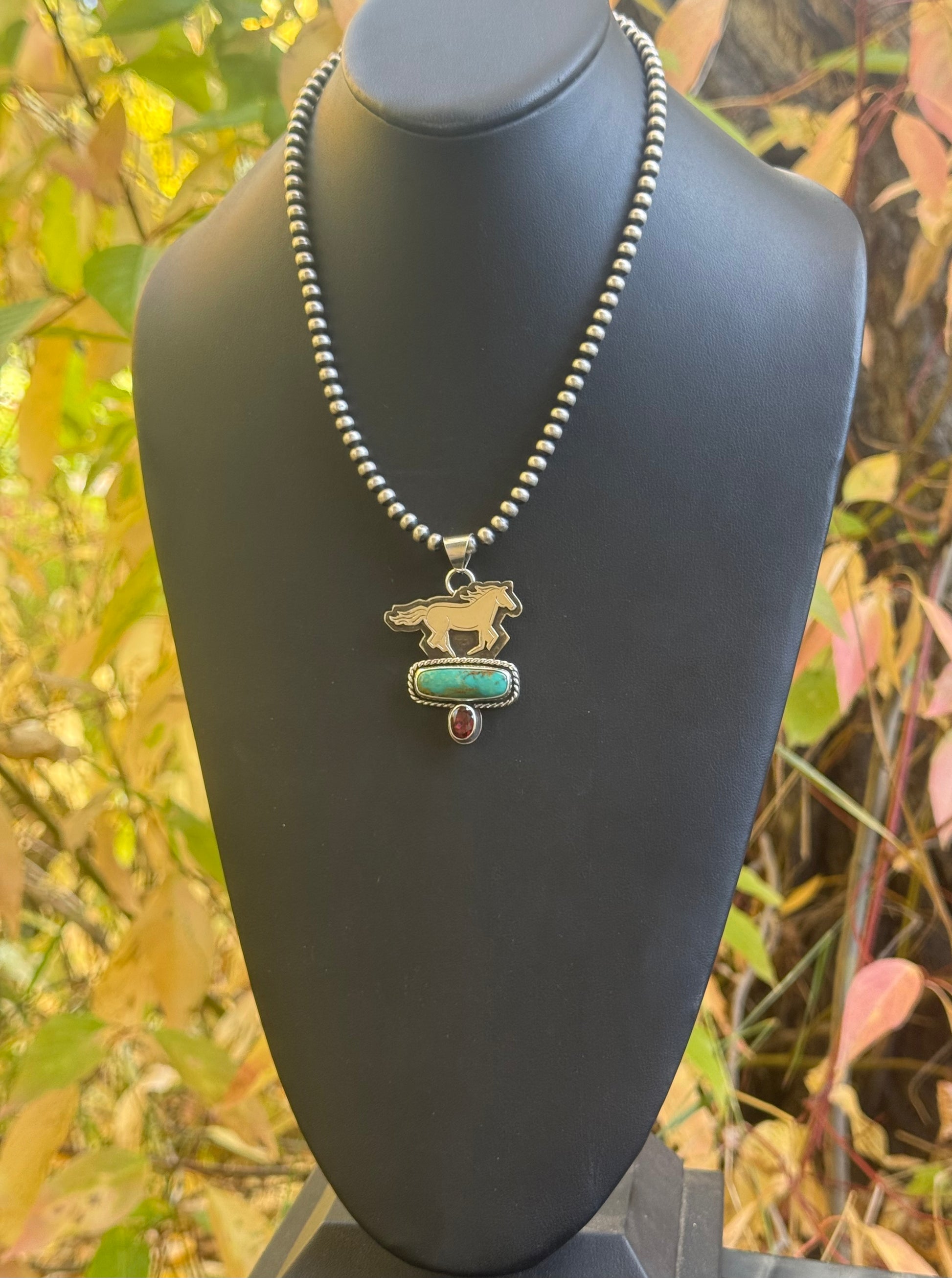 Necklace with a pendant on a black mannequin against a natural background